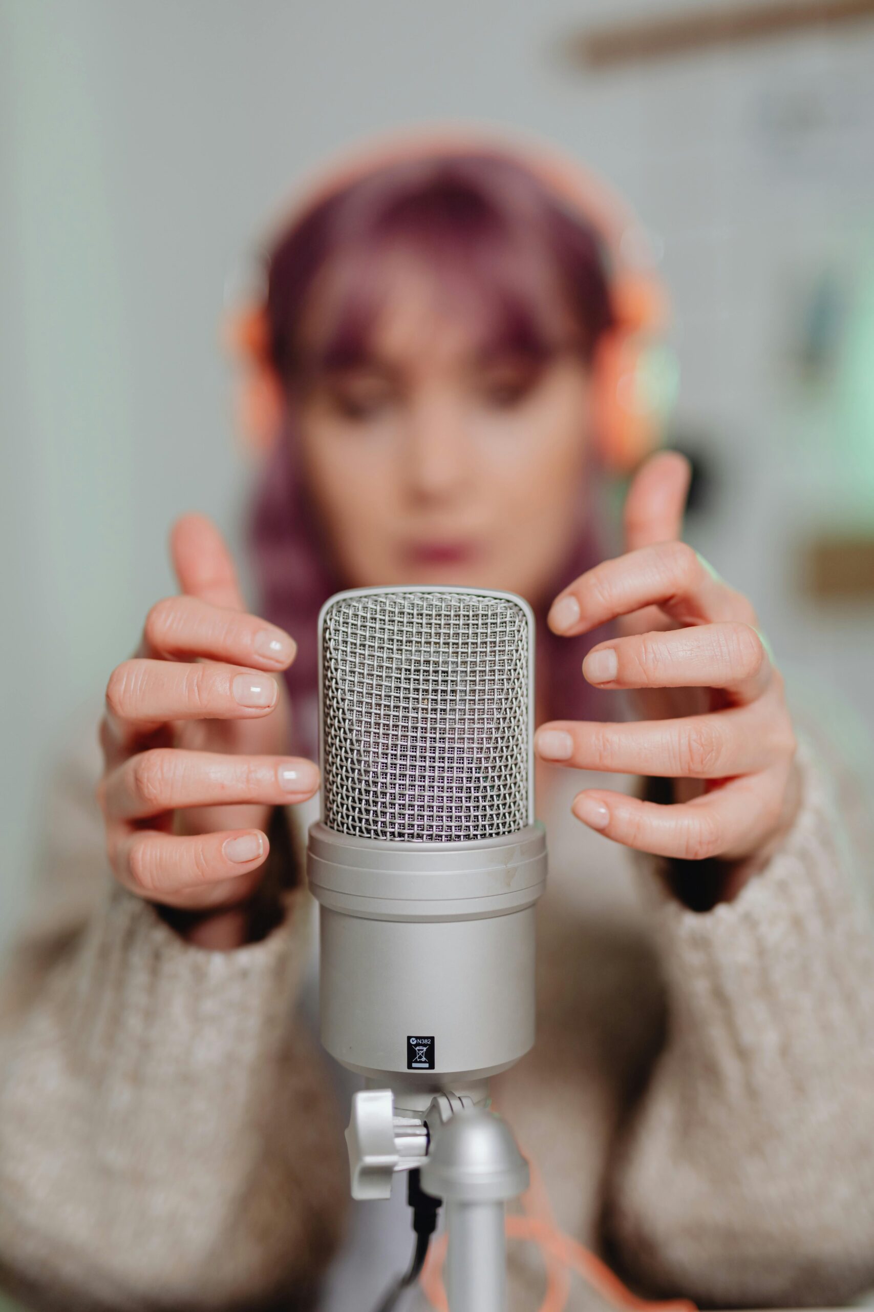 Close-up of a woman recording ASMR with a microphone indoors.